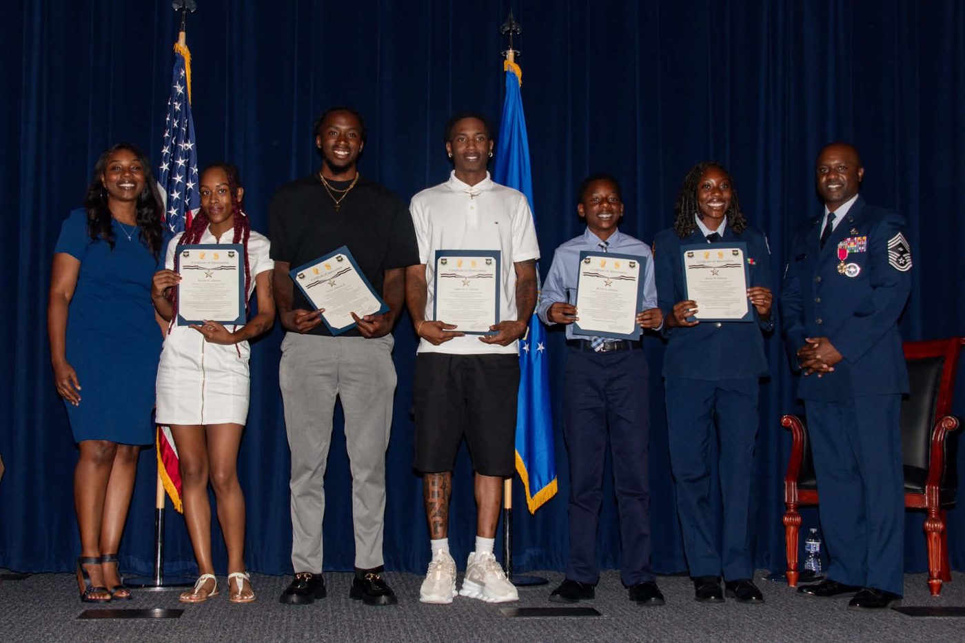 Neco Johnson's family holding certificates of appreciation on stage in front of American and Air Force flags.